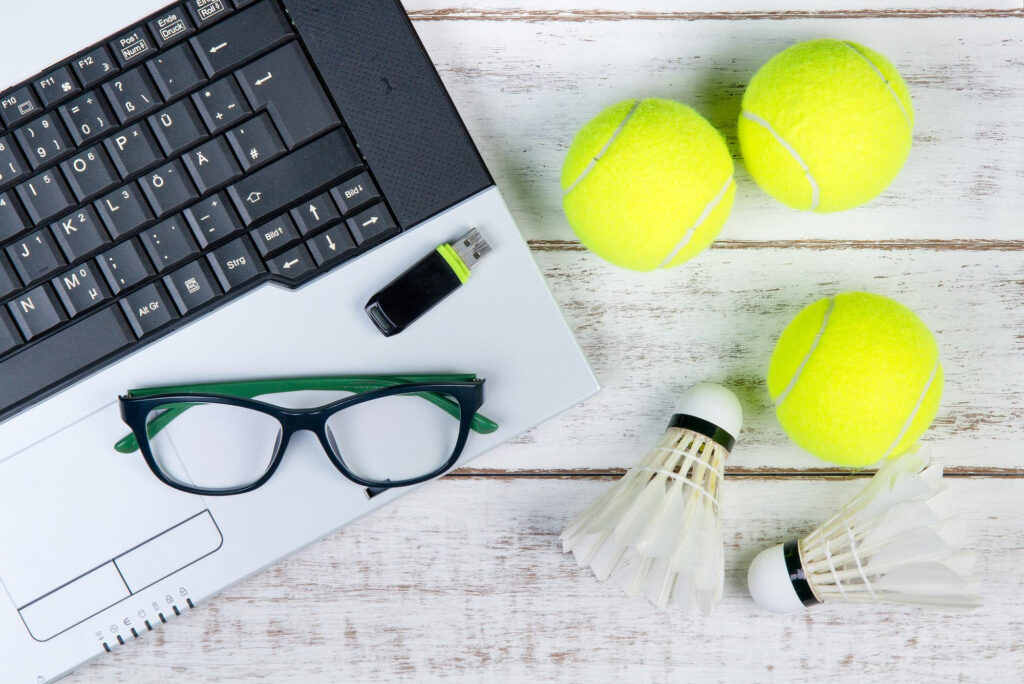 Pelotas de tenis y volantes de badminton junto a un portátil