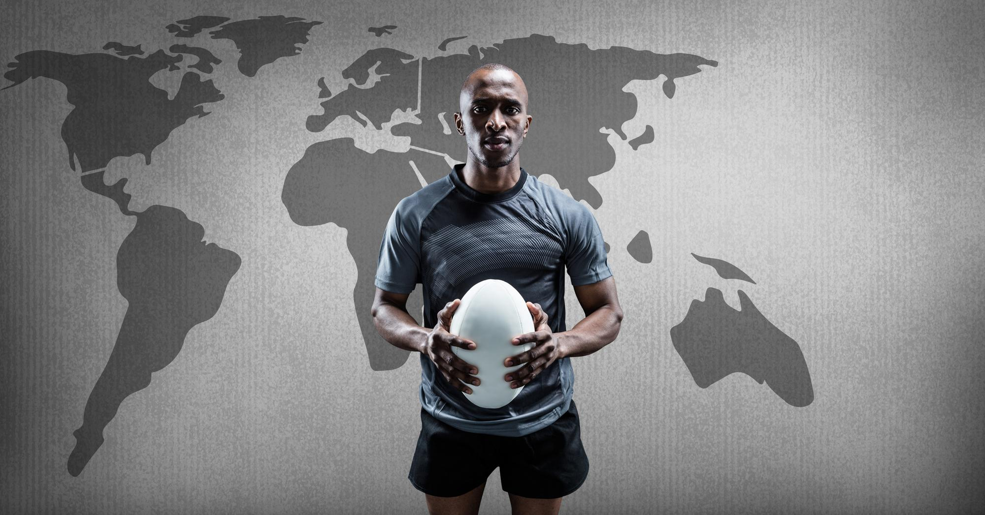 Hombre sujetando balón de rugby frente al mapamundi