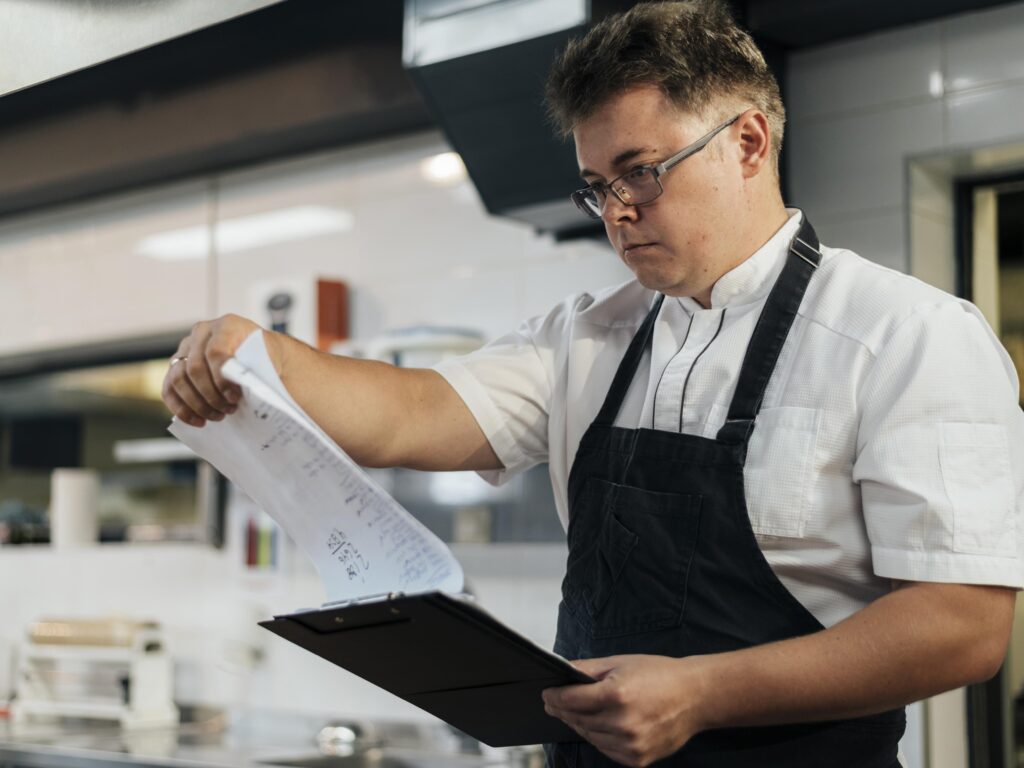 Persona con mandil de cocina revisando unos papeles