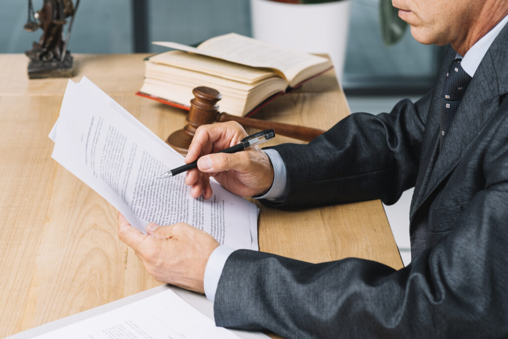 Persona repasando un contrato con un libro de leyes cerca
